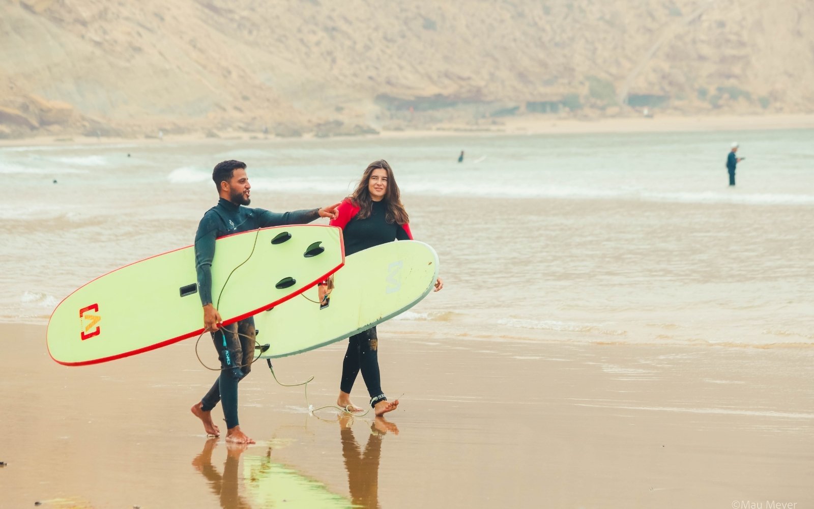 Two surfers walking the beach with their boards